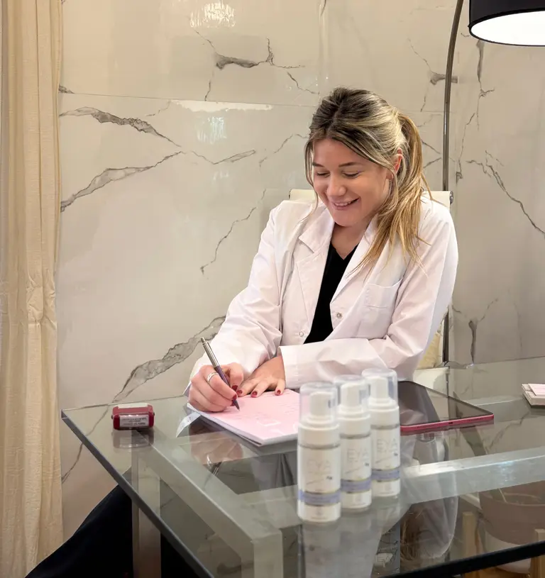 La Dra. Yamila Gorisnic escribiendo en su escritorio del consultorio
